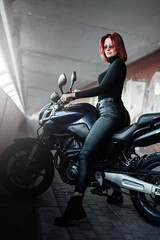 A modern motorbike and female biker with red hairs