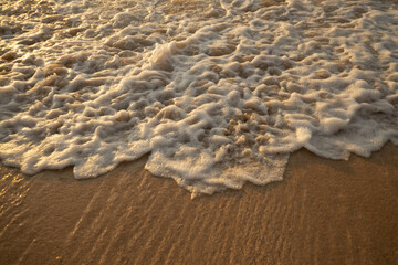 Scenic seascape. Milky foam waves at the beach. Sunset time. Waterscape for background. Selected soft art focus. Sunlight reflection on the water and sand. Balangan beach, Bali, Indonesia