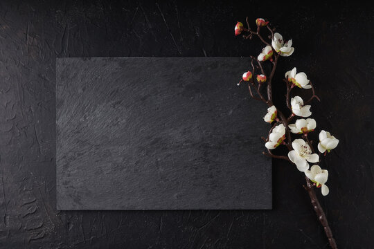 Black stone tray with sakura on a black background Copy space Dark photo Mock up