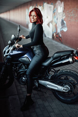 Fototapeta na wymiar Redhead sexy female biker rides her modern motorcycle