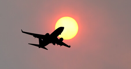 A 737 jet silhouetted against a hazy sun.