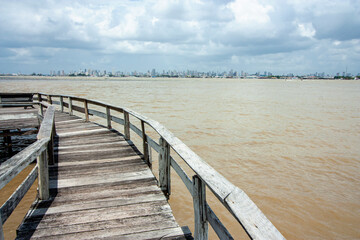 Fototapeta premium Trapiche de madeira na beira do rio na margem do rio Guajará, com Belém do Pará na linha do horizonte.