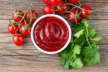 White bowl of tomato sauce with parsley and tomato. Ketchup on natural wooden background