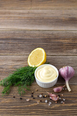 Mayonnaise sauce with garlic, lemon and herbs on wooden background