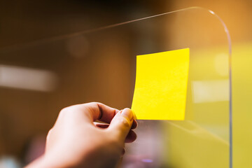 Business people using sticky note on plexiglass separators to share ideas and brainstorming for discussing and planning. New normal Concept for social distancing in the office during the Covid-19.