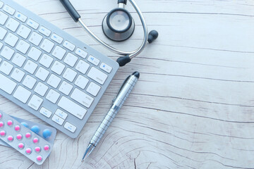 high angle view of pills , keyboard and stethoscope on clinic desk .