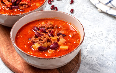 Chili con carne in a bowl on a grey concrete background close-up. Tex-mex food. Delicious spicy...