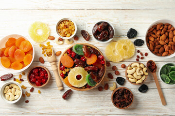 Bowls with dried fruits and nuts on white wooden background