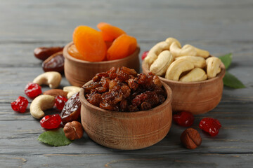 Bowls with dried fruits and nuts on gray wooden background