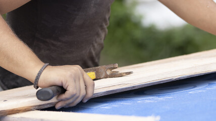 The worker is preparing a batten for nailing to the roof