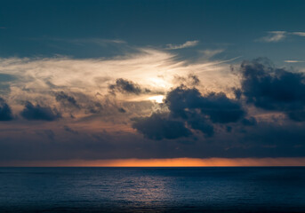 Sunset landscape over the Atlantic sea with clouds hiding the sun.