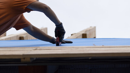 The worker holds the insulation layer with a stapler