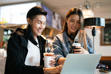 Asian couple take off mask protection uses their laptop computer and smartphone to relax during a flight in lounge at international airport.Young man and woman laugh smile together in coffee shop cafe