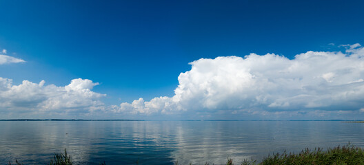 Panorama-Landschaft Wolken spiegeln sich an einem windstillen Tag im Wasser der Flensburger Förde in Schleswig-Holstein