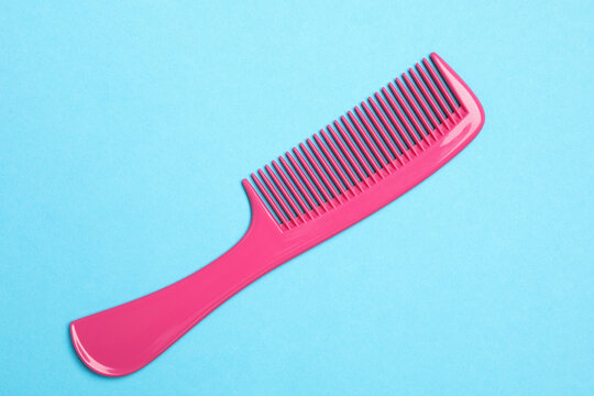 Modern pink hair comb on light blue background, top view