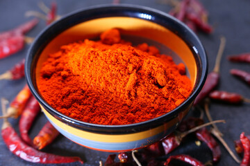 Chili powder and dried peppers on table background.