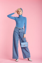 Full body fashion portrait of young elegant model wearing trendy wide leg jeans, light blue...