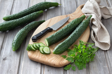 Long Chinese cucumbers on a cutting board while slicing salad. wood background. selective focus