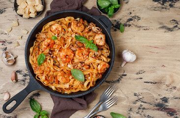 Italian fettuccine pasta with seafood. Seafood pasta with mussels, shrimp and octopus with basil in a cast iron pan
