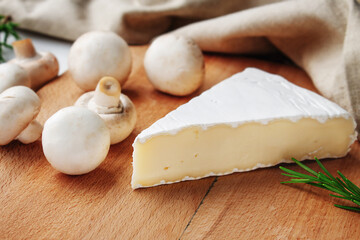 Fototapeta na wymiar Brie cheese on a wooden board with mushrooms and rosemary