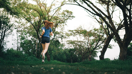 Young lady running at tropical forest trail., at time sunset.