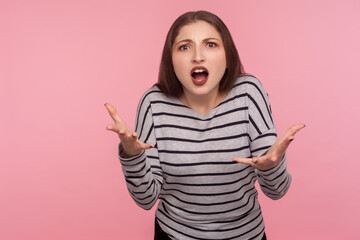 How could you? Portrait of annoyed angry woman in striped sweatshirt raising arms, indignantly asking reason of failure, quarreling and scolding. indoor studio shot isolated on pink background