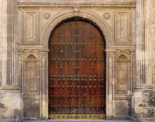 ancient door in the old town with a wooden gate, stone semicircular arch with ornaments in the...