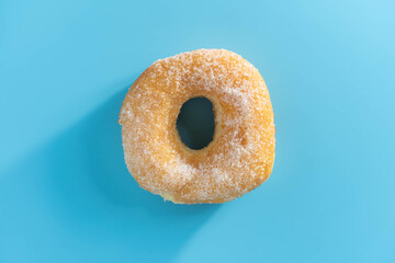 Fototapeta na wymiar Donut dessert sprinkle with sugar Placed on a blue background. Donuts are made from flour like a cake with holes in the center and various flavors.