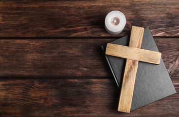 Cross, Bible and burning candle on wooden background, flat lay with space for text. Christian...