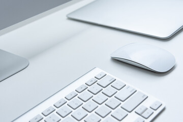 Top view of minimal and clean home office desk workspace with aluminum keyboard, mouse and notebook on white background