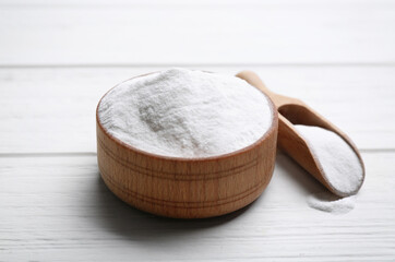Baking soda in bowl on white wooden table