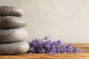 Fototapeta na wymiar Lavender flowers and spa stones on wooden table, closeup. Space for text