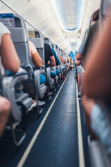 A narrow aisle between the rows of passenger seats in the cabin of a budget airliner - a full plane of tourists is ready to fly © andrey gonchar