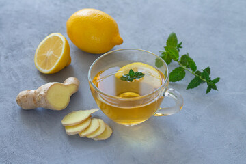 Ginger tea in glass cup with lemon and mint