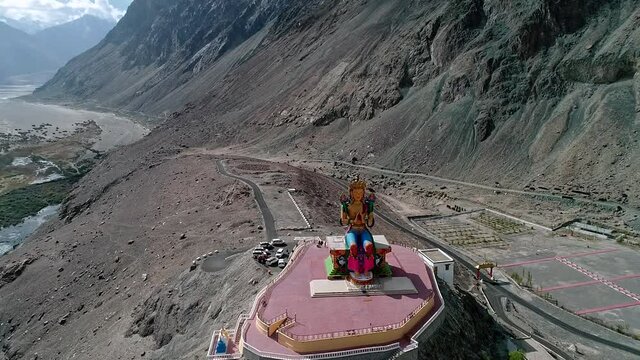 aerial shot of camera slowly flying towards a tall budha statue at diskit gompa, ladakh.