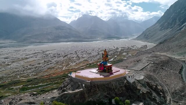 aerial scene of a very distant budha statue with camera moving around slowly in circle