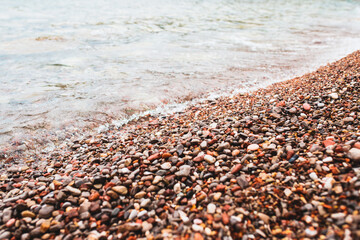 Shoreline on the diagonal of the frame - a combination of sea water and a pebble beach with small stones