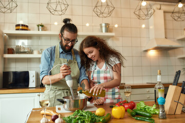 Italian man, chef cook using hand blender while preparing a meal. Young woman, girlfriend in apron...