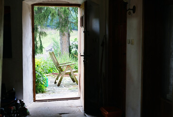 view through the back door of an old cottage on weathered wooden chair in the garden