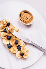 Creamy peanut butter sandwich with banana and blueberry on grey marble tray. Breakfast. Selective focus