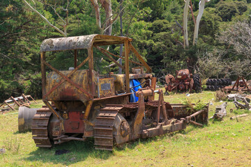 Old, rusty bulldozer, abandoned in a field with other machinery