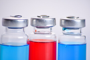 Vaccine, coronavirus vaccination, covid-19 flu prevention, immunization concept. three color red and blue medicine vial or ampoules