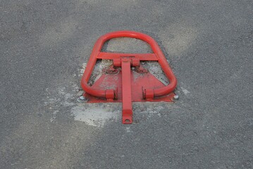 one red metal interlock lies on the gray asphalt of the road in the parking lot