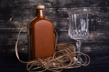Bottle of whiskey and empty wineglass on a black wooden
