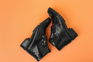 Pair of stylish ankle boots on orange background, top view