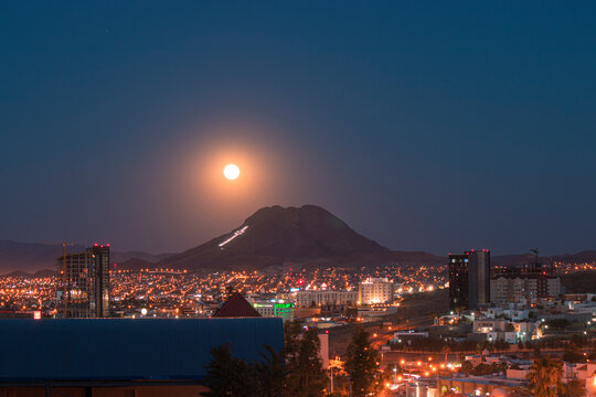 High Angle View Of Full Moon Over City Lit Up At Night
