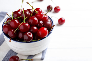 Sweet juicy cherries on white wooden table. Space for text