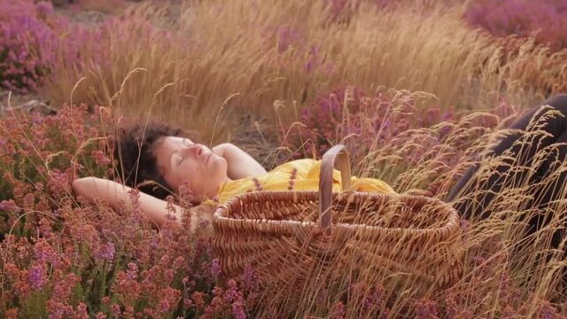 une jeune femme naturelle fait une sieste dans un champ fleurie automnale.
