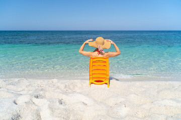 Happy woman enjoying the beach relaxing joyful in the summer by the tropical blue water. Beautiful happy bikini model traveling wearing sun hat on is arutas beach, Sardinia, Italy