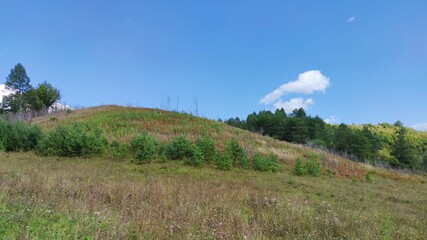 panoramic scene with a hill against the blue sky on a sunny day